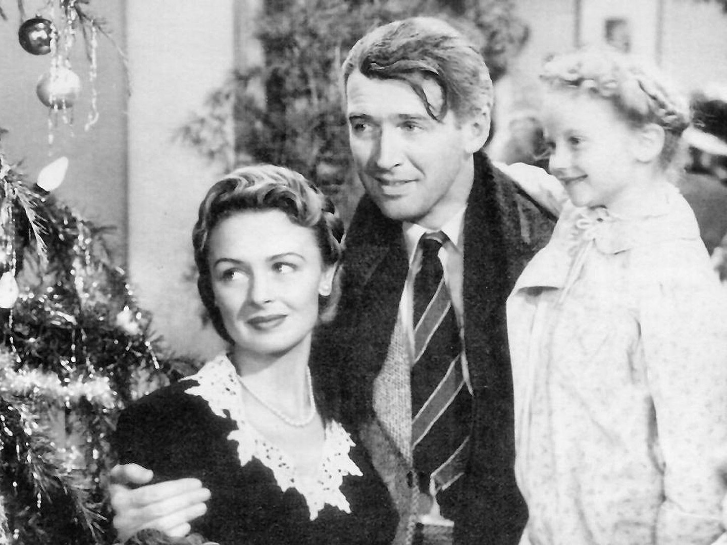 George Bailey hugs his wife, Mary, and holds his daughter, Zuzu, in the movie It's a Wonderful Life